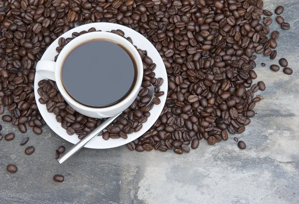 Rykande varm kopp kaffe omgiven av mörkt kaffe bönor med — Stockfoto