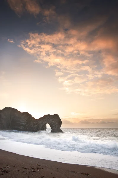 Nasce o sol de inverno colorido atrás da porta Durdle na costa jurássica i — Fotografia de Stock