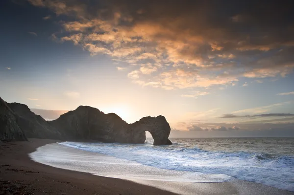Nascer do sol vibrante sobre o oceano com pilha de rocha em primeiro plano — Fotografia de Stock