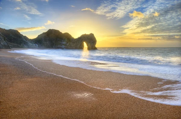 Nascer do sol vibrante sobre o oceano com pilha de rocha em primeiro plano — Fotografia de Stock