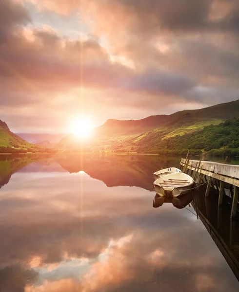 Схід сонця над озером з човнами, пришвартованими на джинсах — стокове фото