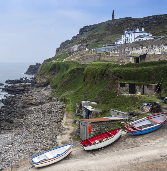 Bateaux de pêche sur cale sous des falaises verdoyantes — Photo