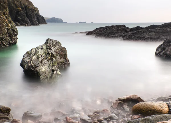 Long exposure flowing tide over and around rocks — Stock Photo, Image
