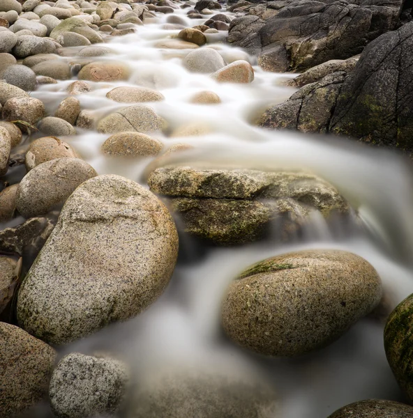 Вода, що носить стародавні скелі деталь на відокремленому пляжі — стокове фото