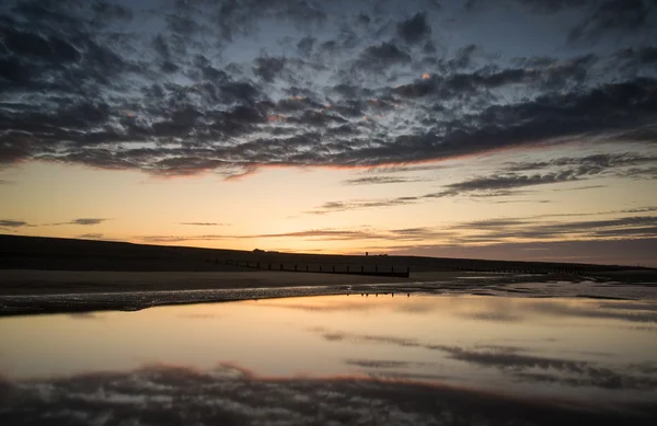 Vibrante paesaggio all'alba riflesso nell'acqua bassa marea sulla spiaggia — Foto Stock