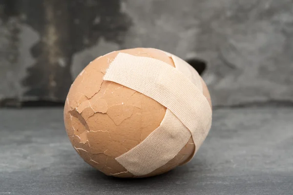Broken healthcare concept image of plaster on egg — Stock Photo, Image