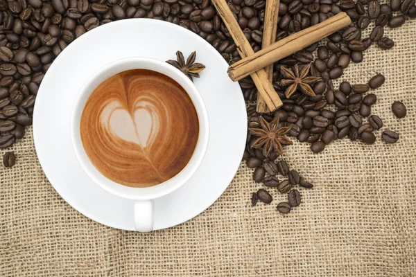 Cup of coffee with heart shape in foam on hessian background — Stock Photo, Image