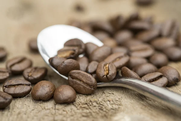 Coffee beans and spoon on wooden background — Stock Photo, Image