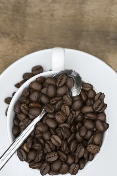 Taza de café y frijoles sobre fondo de madera — Foto de Stock