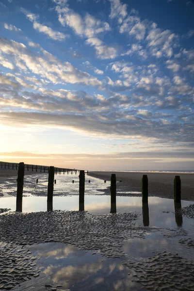 Paisagem vibrante do nascer do sol refletida na água da maré baixa na praia — Fotografia de Stock