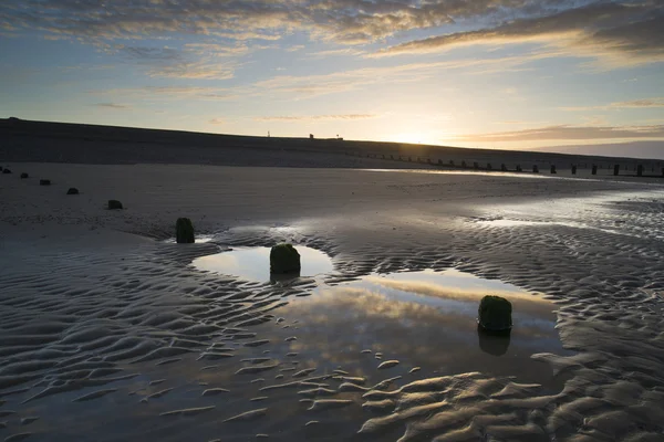 Paisagem vibrante do nascer do sol refletida na água da maré baixa na praia — Fotografia de Stock