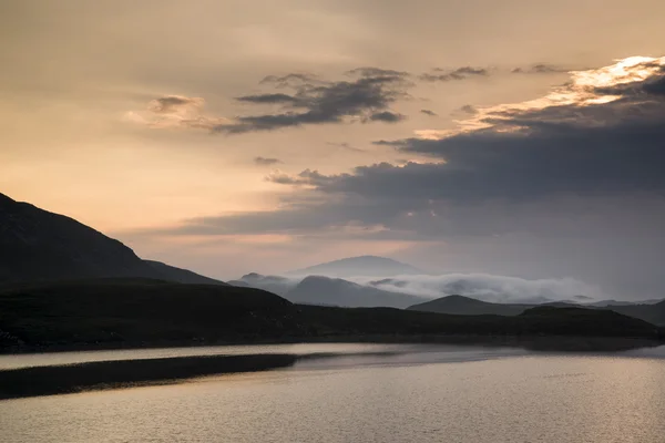Neblige Berglandschaft bei Sonnenaufgang spiegelt sich im See wider — Stockfoto