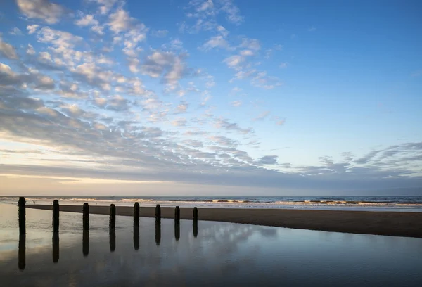 Paisagem vibrante do nascer do sol refletida na água da maré baixa na praia — Fotografia de Stock