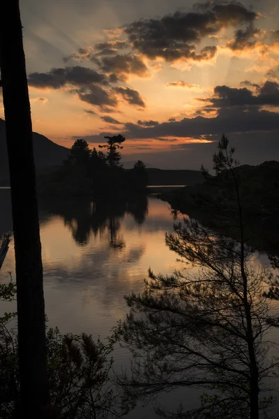 Impresionante silueta de montañas lago y rayos de sol amanecer tierras —  Fotos de Stock