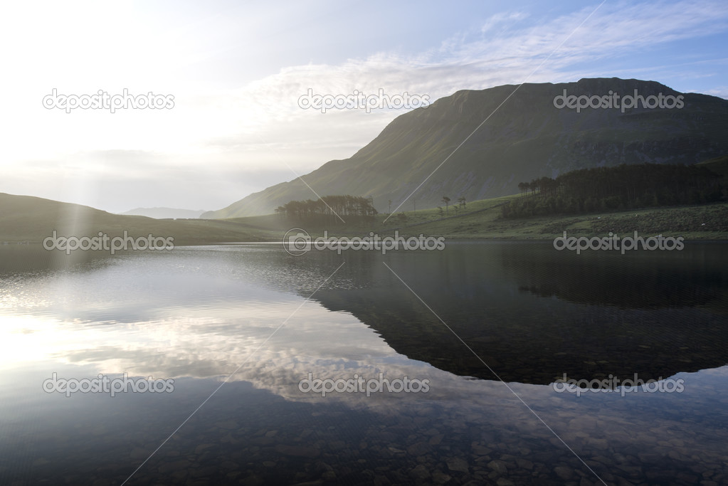 Beautiful sunrise mountain landscape reflected in calm lake