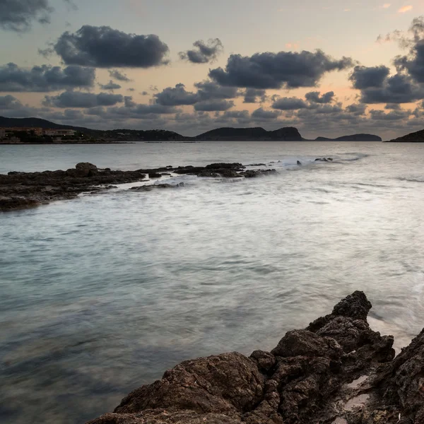 Приголомшливий пейзажний світанок схід сонця з кам'янистою береговою лінією і довгим часом — стокове фото