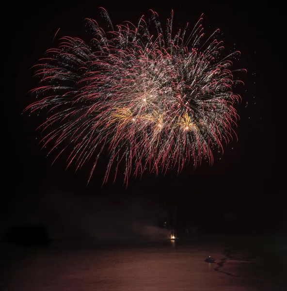 Fireworks display over sea with reflections in water — Stock Photo, Image