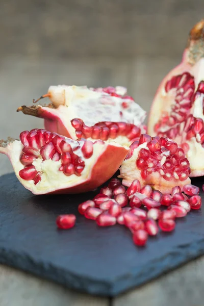 Färska öppen granatäpple med frön ut på skiffer bas och trä b — Stockfoto