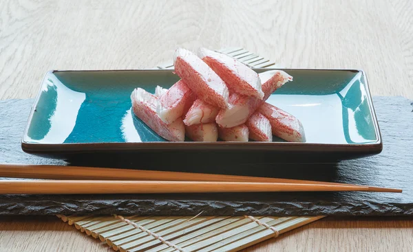 Fresh raw sushi crabsticks on plate with chopsticks — Stock Photo, Image