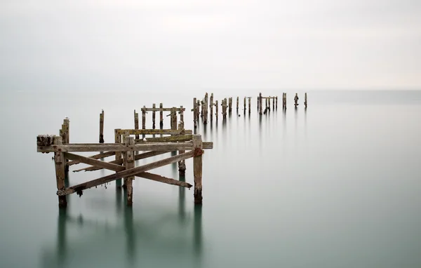 Fine immagine del paesaggio artistico del molo abbandonato nella lunga esposizione lattiginosa — Foto Stock