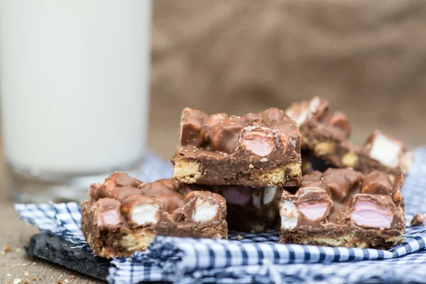 Rustic background with rocky road dessert squares with glass of — Stock Photo, Image