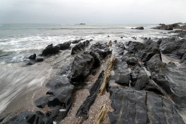 Landscape seascape of jagged and rugged rocks on coastline with — Stock Photo, Image