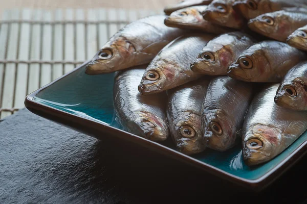 Fresh tasty raw sprats on serving dish — Stock Photo, Image