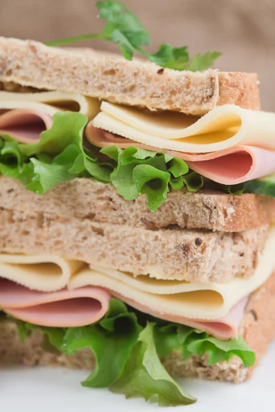 Presunto fresco e queijo em sanduíche branco em ambiente de cozinha rústica — Fotografia de Stock