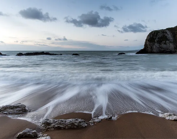 Praia paisagem do nascer do sol com ondas de exposição longa movimento — Fotografia de Stock