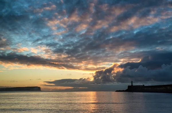 Vacker pulserande soluppgång himlen över lugna vatten havet med lightho — Stockfoto