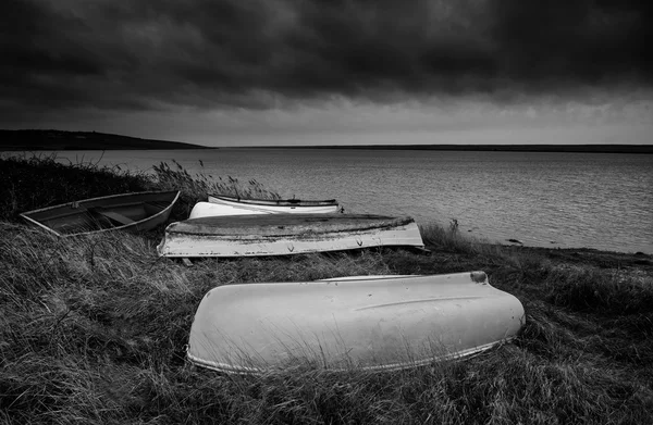 Old decayed rowing boats on shore of lake with stormy sky overhe — Stock Photo, Image