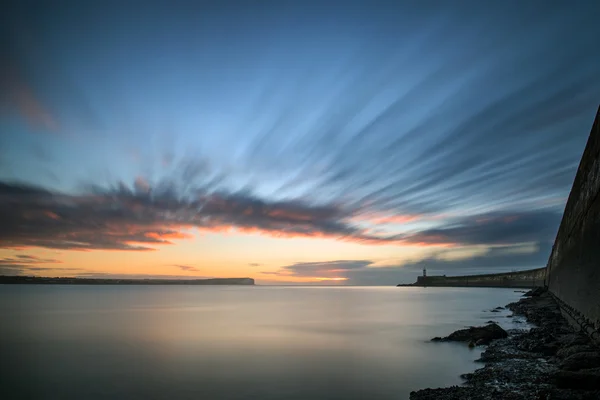 Prachtige levendige zonsopgang hemel over kalm water Oceaan met lightho — Stockfoto