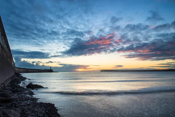 Beautiful vibrant sunrise sky over calm water ocean with lightho — Stock Photo, Image