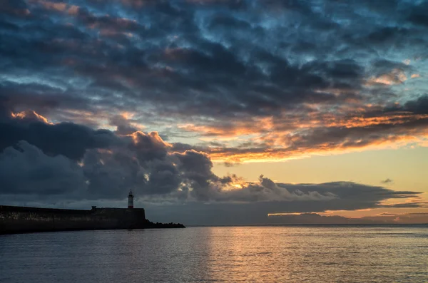 Schönen lebendigen Sonnenaufgang Himmel über ruhigem Wasser Ozean mit Leuchtfeuer — Stockfoto