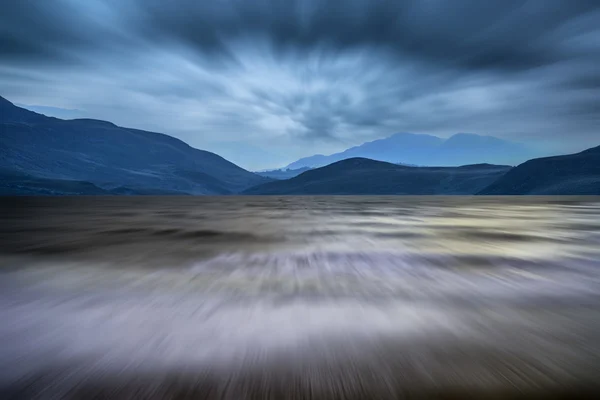 Long exposure landscape of stormy sky and mountains over lake — Stock Photo, Image