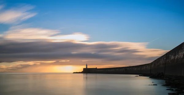 Beautiful vibrant sunrise sky over calm water ocean with lightho — Stock Photo, Image