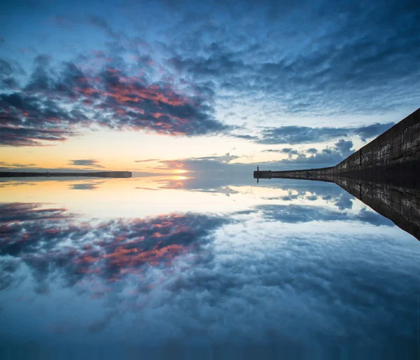 Beautiful vibrant sunrise sky over calm water ocean with lightho — Stock Photo, Image