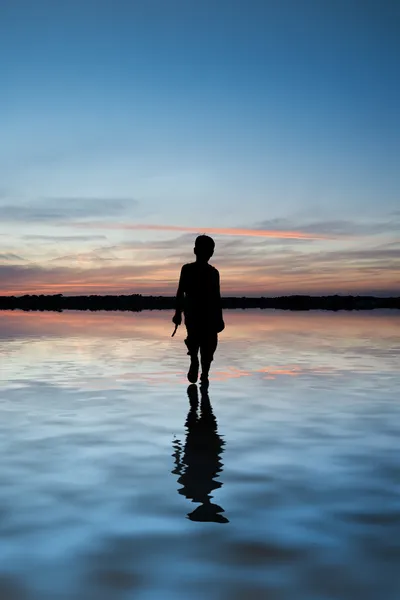 Koncept obraz mladého chlapce, chůze po vodě v krajině při západu slunce — Stock fotografie