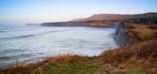 Beautiful coastal landscape at sunrise with cliffs and misty glo — Stock Photo, Image