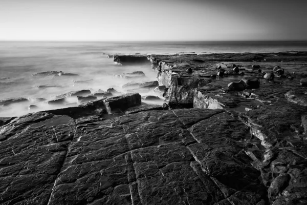 Beautiful coastal landscape at sunrise with cliffs and misty glo — Stock Photo, Image