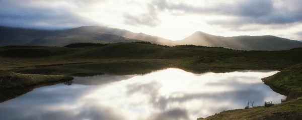 Panorama paisagem nascer do sol sobre montanhas e lago em primeiro plano — Fotografia de Stock