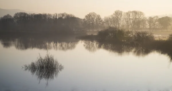 Paisagem do lago em névoa com brilho solar ao nascer do sol — Fotografia de Stock