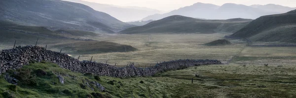 Panoramautsikt landskapet genom dimmiga soluppgång i bergspass — Stockfoto