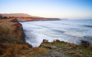 sunrise olan kayalıklarla ve puslu glo adlı güzel sahil peyzaj