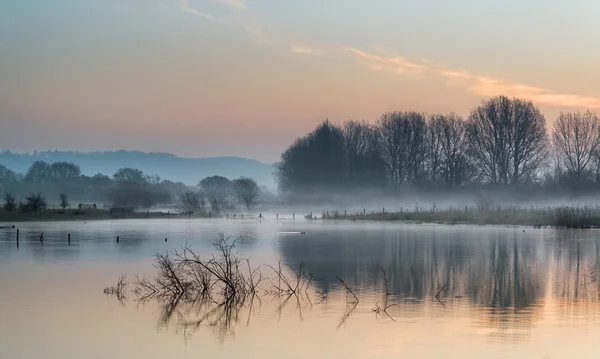 Landschap van lake in mist met zon gloed bij zonsopgang — Stockfoto