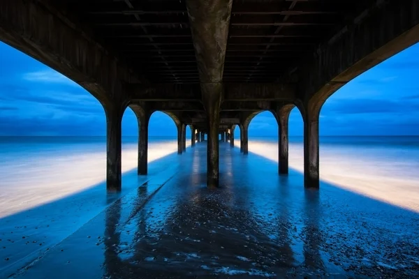 Twilight dusk landscape of pier stretching out into sea with moo — Stock Photo, Image