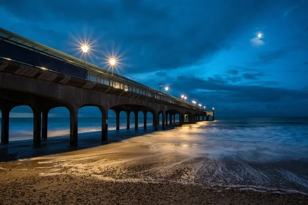 Twilight dusk landscape of pier stretching out into sea with moo — Stock Photo, Image