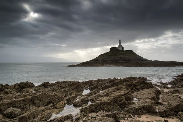 Faro en el promontorio con rayos de sol sobre el paisaje oceánico con —  Fotos de Stock