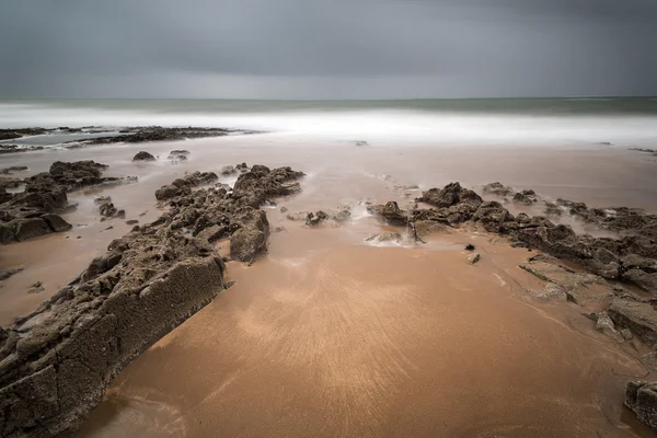 Longa exposição paisagem praia cena com céu mal-humorado — Fotografia de Stock