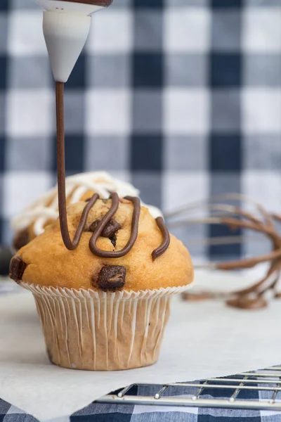 Icing frosting being put onto home made chocolate chip muffins — Stock Photo, Image